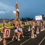 Varsity cheerleaders lead the away game crowd as dark skies loom overhead. The Waller Bulldog football team slips against Conroe Grand Oaks, 17-14, for the Bulldog’s first loss of the 2024 campaign, at Moorehead Stadium in Conroe, Sept. 5, 2024. (Photo by Creighton Holub, courtesy RoninVisuals.com)